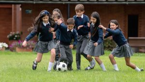 Chicas y chicos jugando a fútbol en el colegio